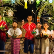 Loy Krathong at The Bush Camp Chiang Mai: children in Karen dress Children in traditional dress holding krathong under a lantern arch at night during Loy Krathong at The Bush Camp Chiang Mai